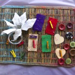 A crayon becoloured placemat with a collaged arrangement of buttons, fabric samples, pegs and a flower.... simply says "FUN". Photo by Bronwyn Holmes.