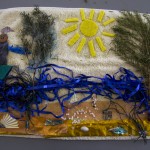 Ribbony river, Raffia riverbed, wattle trees, sponge sun, all on a textured towelling background. This is a lovely scene of the Nepean river all made from recycled materials. Photo by Bronwyn Holmes.